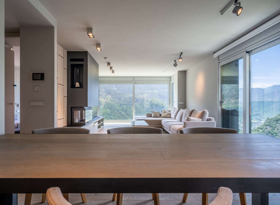 Modern mountain view home with open floor plan, featuring a large sectional sofa and dining table.