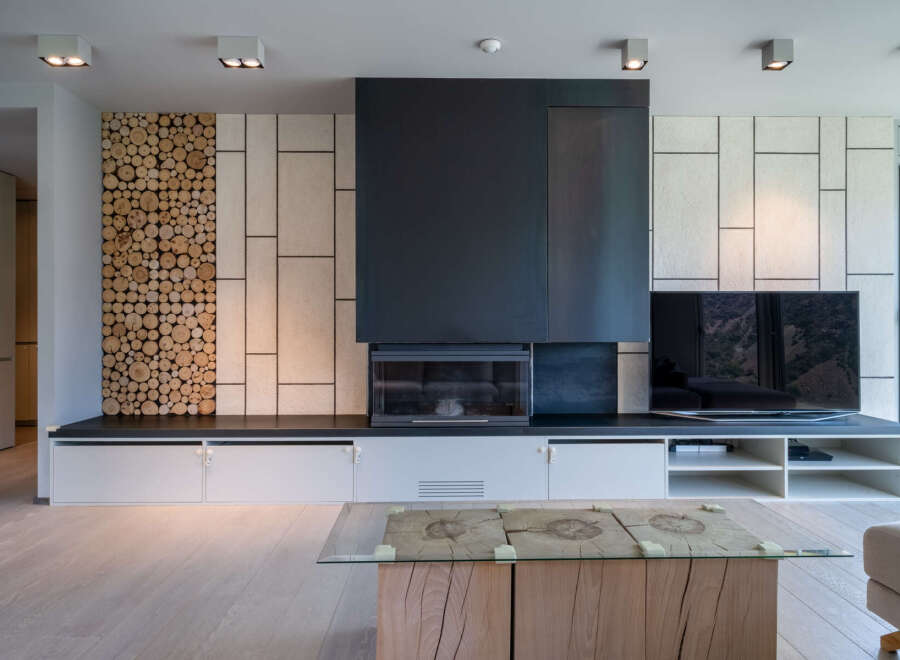 Stunning modern living room with a unique wood-stacked feature wall, sleek fireplace, and built-in entertainment center.