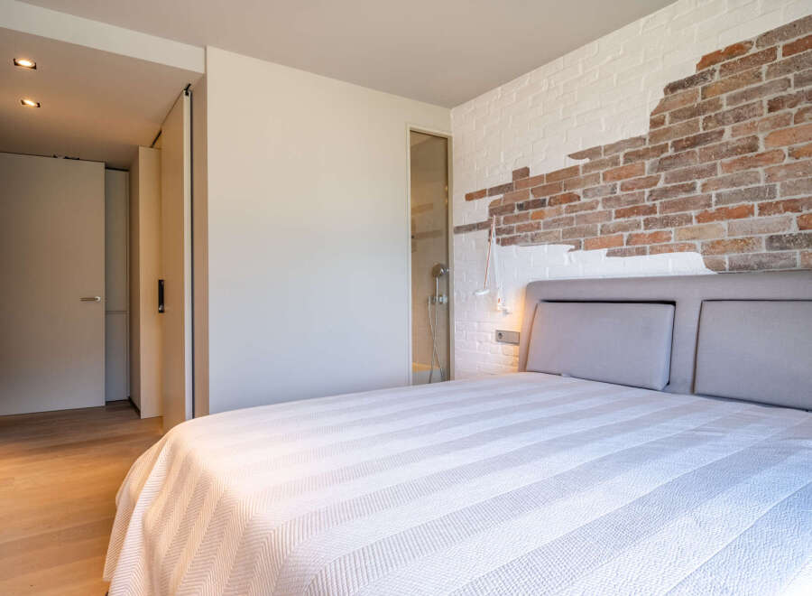 This stunning bedroom boasts a unique brick feature wall, adding character and texture to the space.