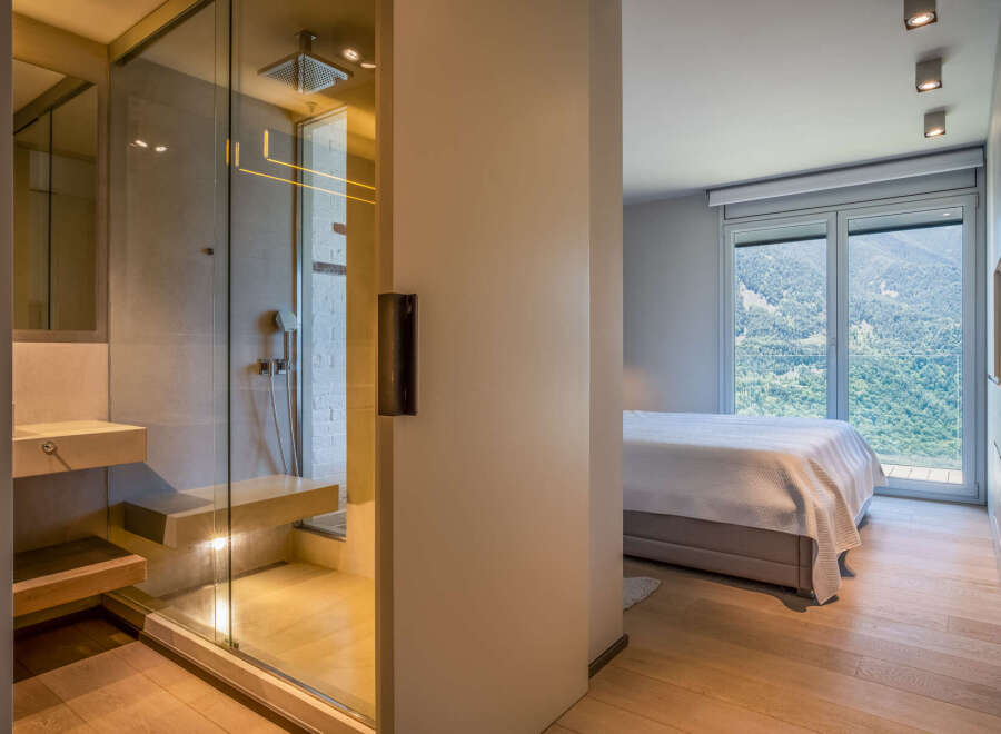Modern bedroom with ensuite bathroom featuring a glass shower enclosure and built-in bench.