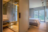 Modern bedroom with ensuite bathroom featuring a glass shower enclosure and built-in bench.