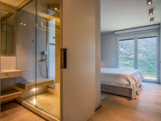 Modern bedroom with ensuite bathroom featuring a glass shower enclosure and built-in bench.