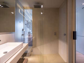 Modern bathroom with a glass shower enclosure, sleek sink, and exposed brick wall.