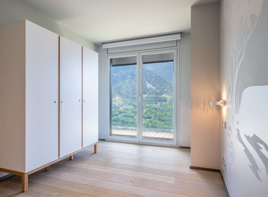 This stunning bedroom boasts a built-in wardrobe and large windows offering breathtaking mountain views.