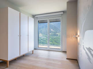 This stunning bedroom boasts a built-in wardrobe and large windows offering breathtaking mountain views.