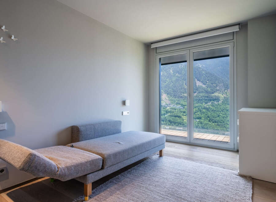 Modern mountain view room with comfortable daybed and large window.