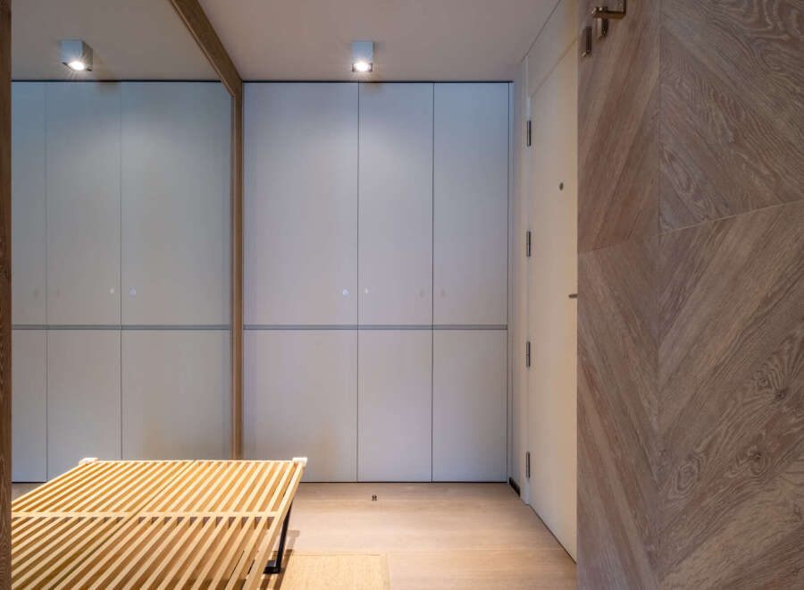 Modern hallway with built-in storage and wooden slatted bench.