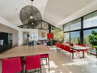 Stunning modern home boasts an open-concept kitchen and dining area with floor-to-ceiling windows offering breathtaking views.