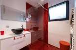 This stunning bathroom boasts a modern design with a sleek white vanity and a vibrant red mosaic tile shower.