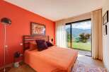 Wake up to breathtaking mountain views from this vibrant orange bedroom.