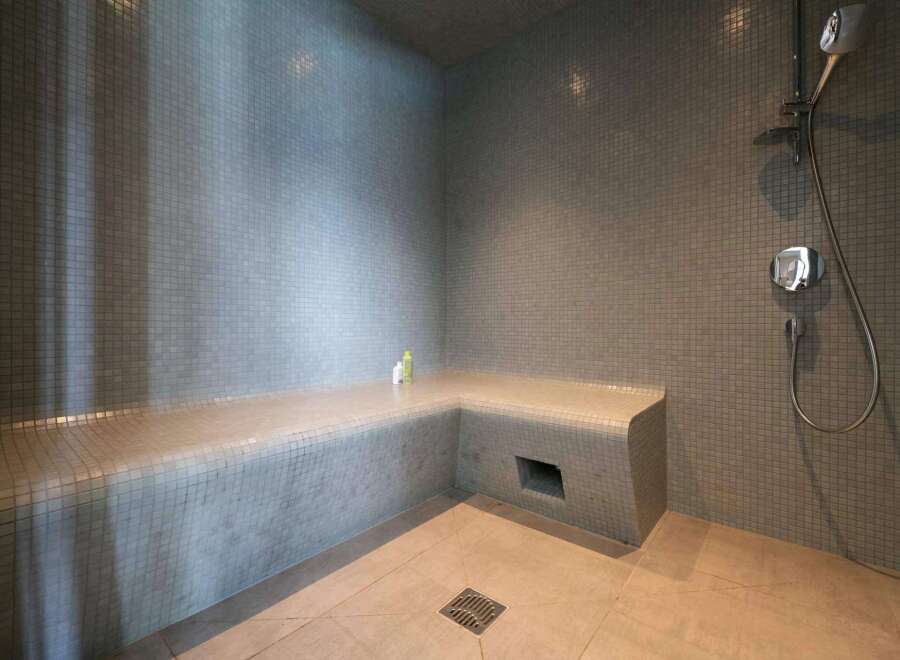 Indulge in this luxurious steam shower, featuring a built-in tiled seat for ultimate relaxation.