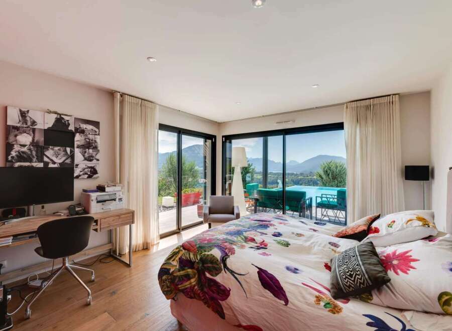 Wake up to breathtaking views from this luxurious bedroom, featuring floor-to-ceiling windows showcasing stunning mountain scenery and a private pool.