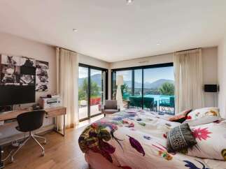 Wake up to breathtaking views from this luxurious bedroom, featuring floor-to-ceiling windows showcasing stunning mountain scenery and a private pool.