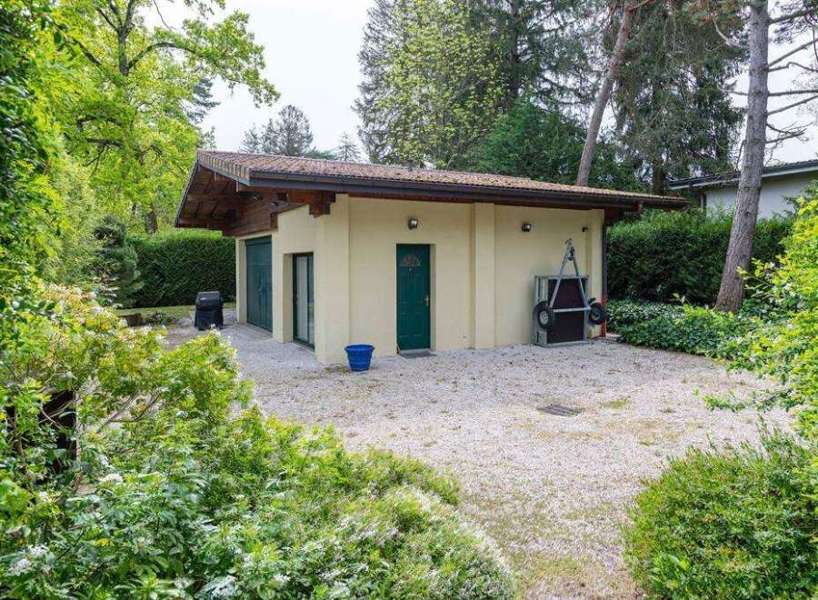 Charming detached garage nestled in a lush green landscape, offering ample storage space and a tranquil setting.