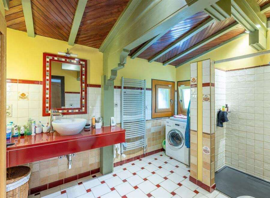 Charming bathroom with rustic wooden ceilings and red accents.