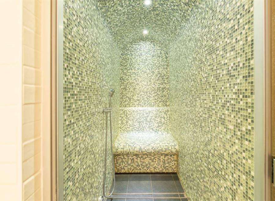 Indulge in ultimate relaxation with this exquisite steam shower, boasting a stunning mosaic tile design and a built-in seat.