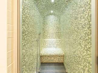 Indulge in ultimate relaxation with this exquisite steam shower, boasting a stunning mosaic tile design and a built-in seat.