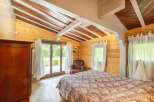 This stunning bedroom boasts a unique wooden ceiling and large windows overlooking a tranquil garden.