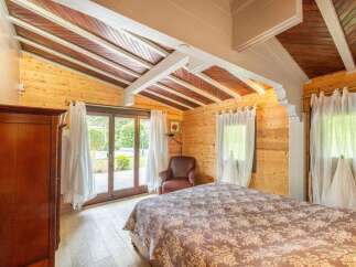 This stunning bedroom boasts a unique wooden ceiling and large windows overlooking a tranquil garden.