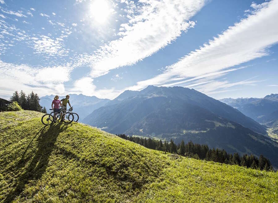 Couple enjoying a scenic mountain bike ride with breathtaking views of the Alps.