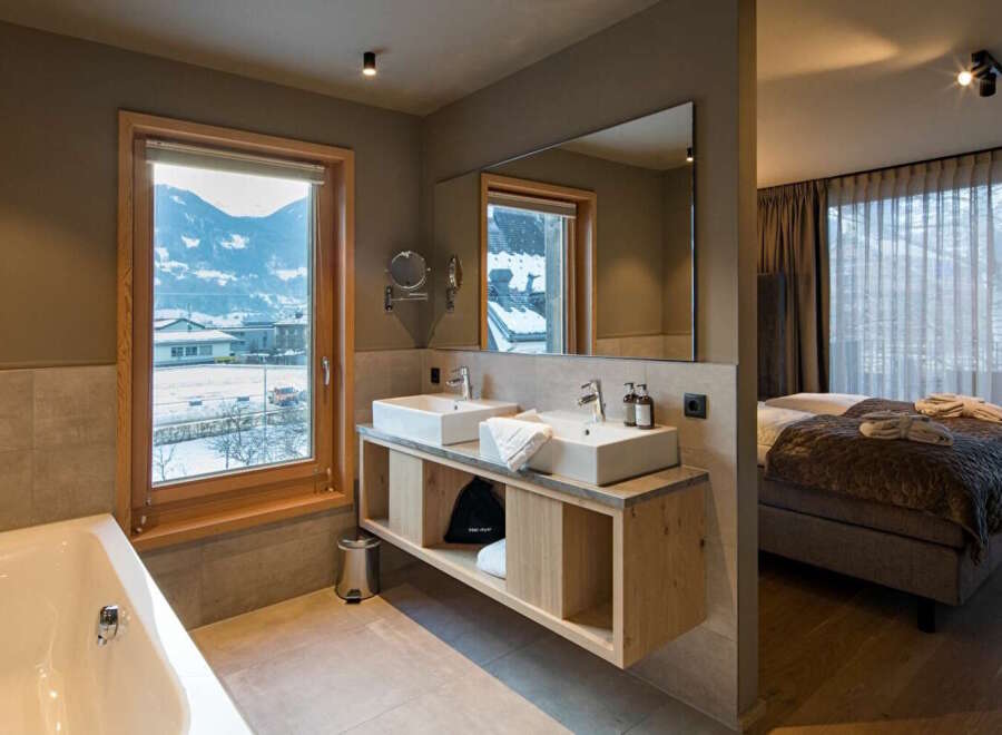 This luxurious bathroom boasts a stunning mountain view from its large window, complemented by a spacious double vanity and a relaxing bathtub.