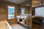 This luxurious bathroom boasts a stunning mountain view from its large window, complemented by a spacious double vanity and a relaxing bathtub.
