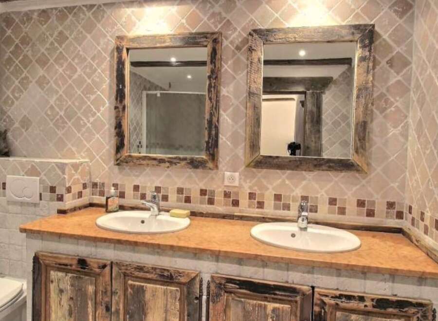 Rustic bathroom with double vanity and antique mirrors.