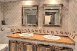 Rustic bathroom with double vanity and antique mirrors.