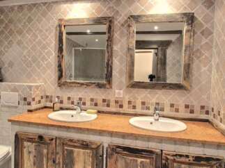 Rustic bathroom with double vanity and antique mirrors.