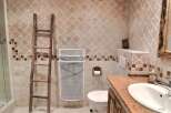 Rustic bathroom with unique tile work and wooden ladder.