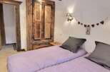 Cozy chalet bedroom with rustic wooden wardrobe and lavender bedding.