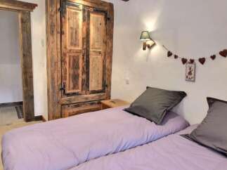 Cozy chalet bedroom with rustic wooden wardrobe and lavender bedding.
