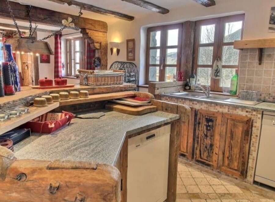 Rustic mountain kitchen with exposed beams, granite countertops, and custom wooden cabinetry.