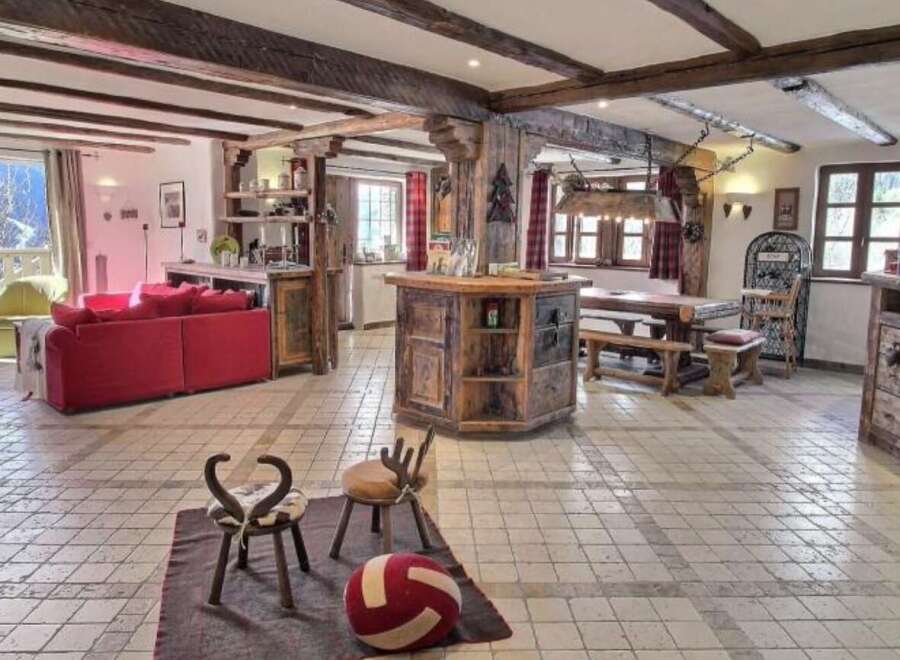 This stunning chalet boasts a spacious open-plan living area with exposed wooden beams, creating a warm and inviting atmosphere.