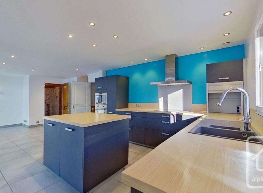 This stunning kitchen boasts modern gray cabinetry, light wood countertops, and a bright turquoise accent wall.