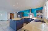 This stunning kitchen boasts modern gray cabinetry, light wood countertops, and a bright turquoise accent wall.