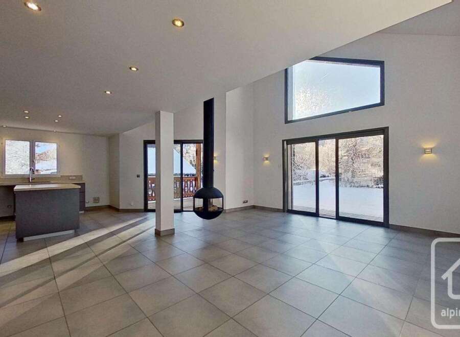 This stunning chalet boasts an open-plan living area with a modern kitchen and large windows offering breathtaking views.