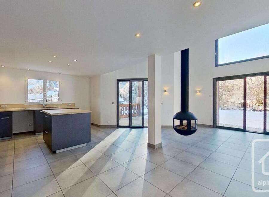 This stunning modern chalet boasts an open-plan living area with floor-to-ceiling windows offering breathtaking views, a sleek designer kitchen, and a unique suspended fireplace.