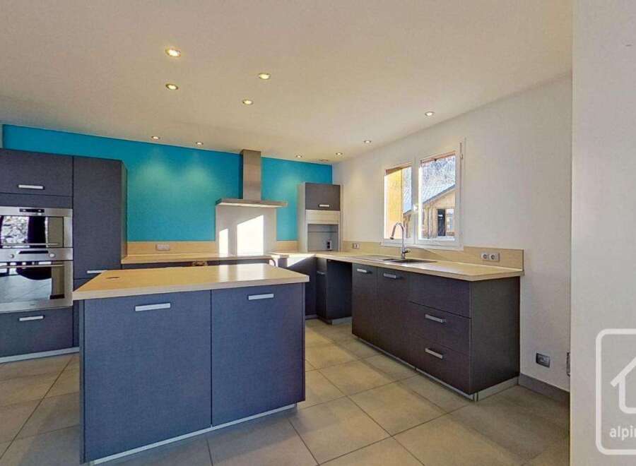 This stunning kitchen boasts modern gray cabinetry, complemented by a vibrant teal accent wall.
