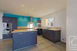This stunning kitchen boasts modern gray cabinetry, complemented by a vibrant teal accent wall.