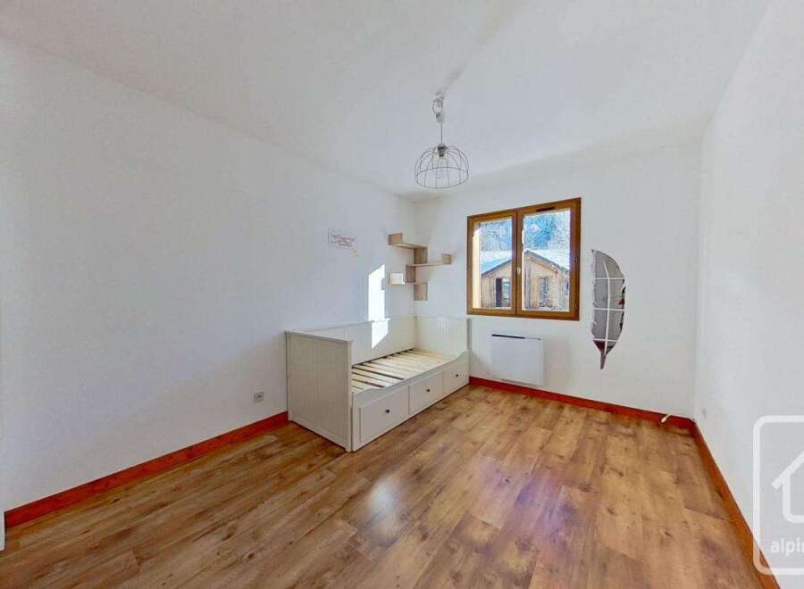 Charming bedroom with wooden flooring, built-in storage, and a day bed.