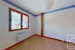 This bright and airy bedroom features a large window offering stunning views of the surrounding mountains.
