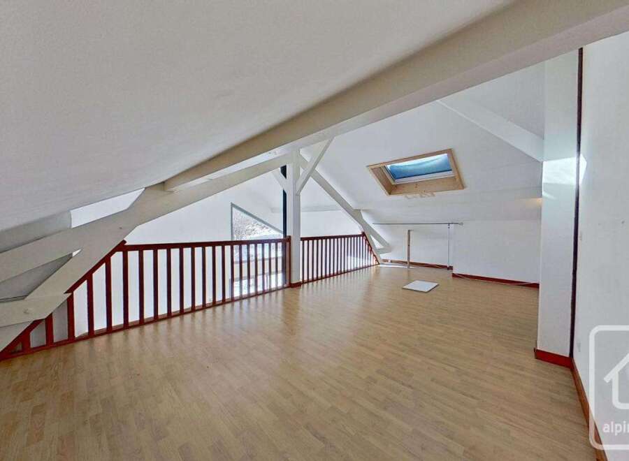 This attic conversion boasts a spacious open-plan layout with light wood flooring, offering versatile living space.