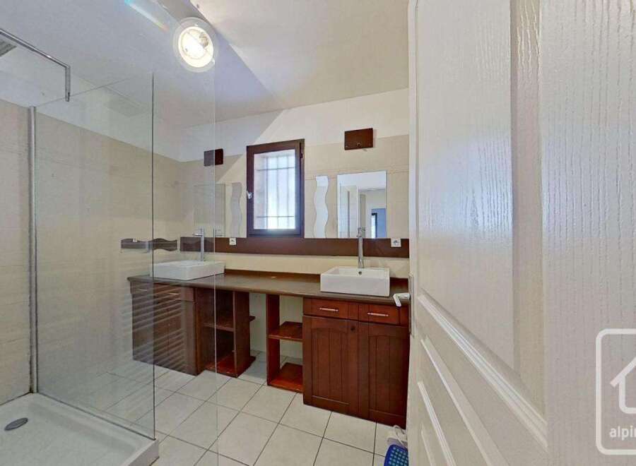 This stunning bathroom boasts a spacious double vanity with ample storage, a large walk-in shower, and elegant dark wood cabinetry.