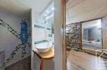 Unique bathroom with a mosaic-tiled shower and a rustic wooden sink vanity.