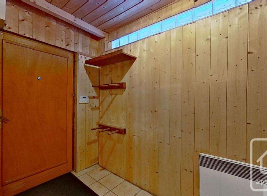 This charming property boasts a spacious entrance hall with wooden wall paneling and built-in shelving, perfect for storage.