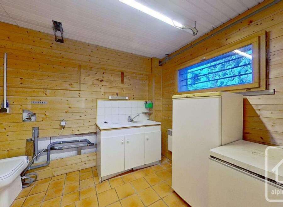 This cozy chalet-style property boasts a practical utility room, complete with a toilet, sink, and ample storage.