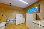This cozy chalet-style property boasts a practical utility room, complete with a toilet, sink, and ample storage.