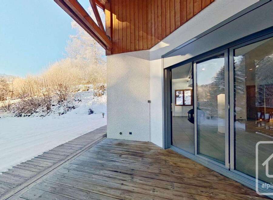This stunning property boasts a spacious deck overlooking a snow-covered landscape, perfect for enjoying the serene winter views.
