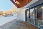 This stunning property boasts a spacious deck overlooking a snow-covered landscape, perfect for enjoying the serene winter views.